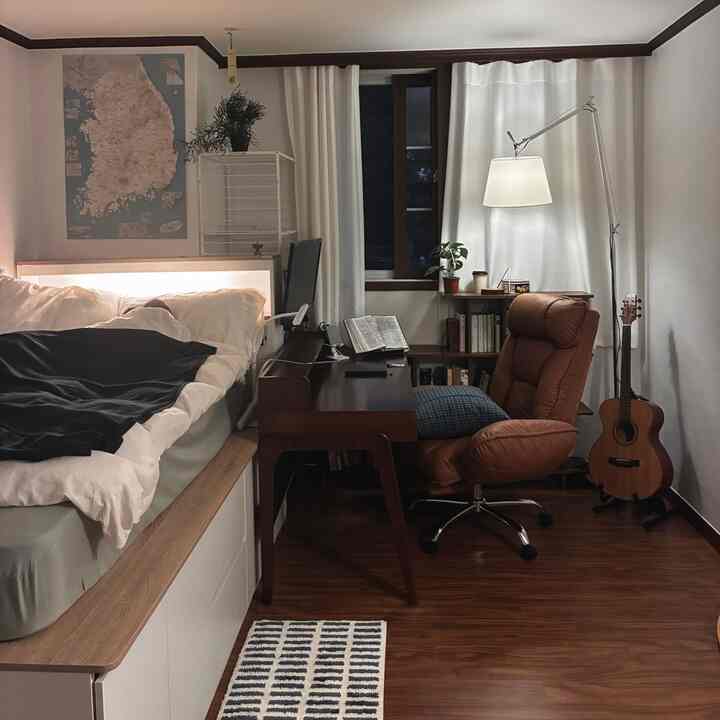 ナチュラルなブラウン調のワンルーム寝室兼ホームオフィス、ベッドとデスク、オフィスチェアが配置された温かみのある空間