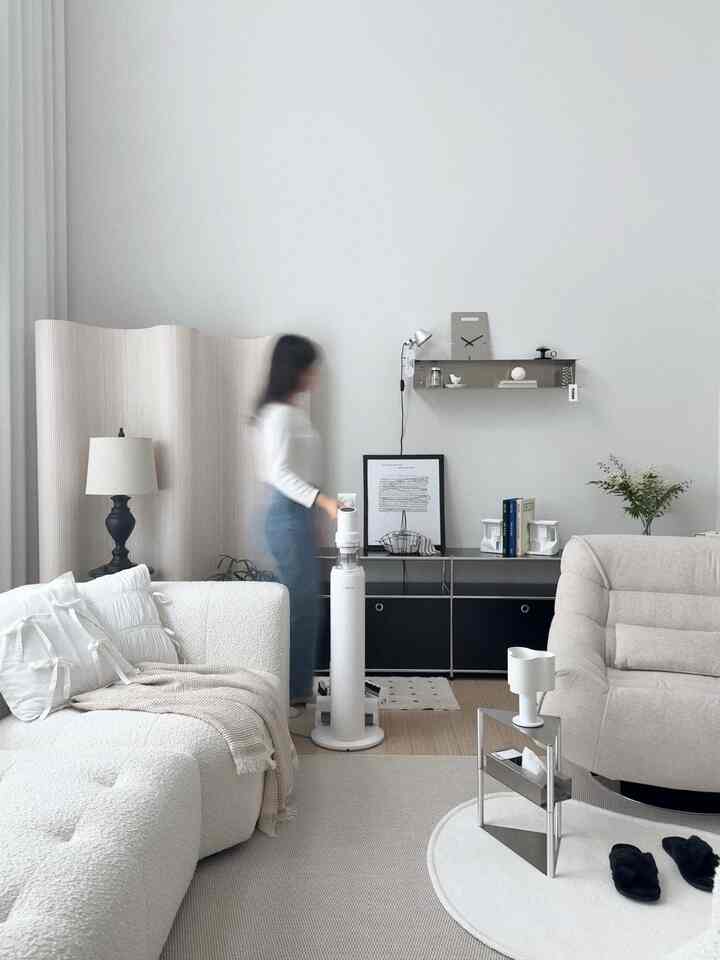 ホワイトとライトブラウンの色調のリビング、シンプルモダンなソファとラグ、壁棚とフロアランプが配置された落ち着いた雰囲気のインテリア