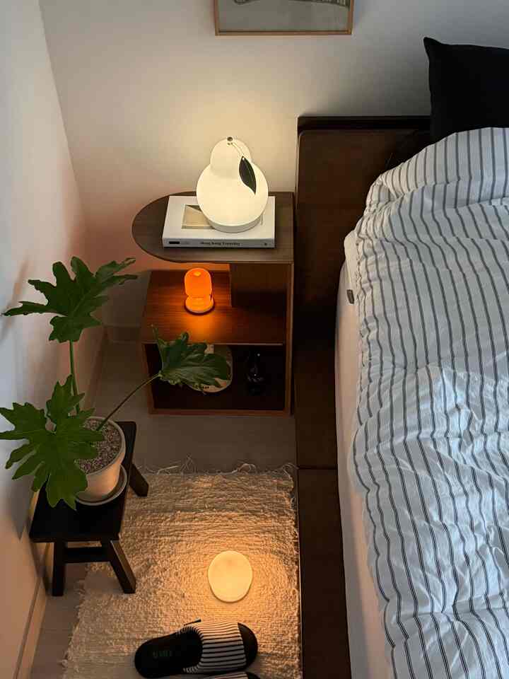 Cozy bedroom in warm brown and white tones featuring a nightstand and ambient lighting