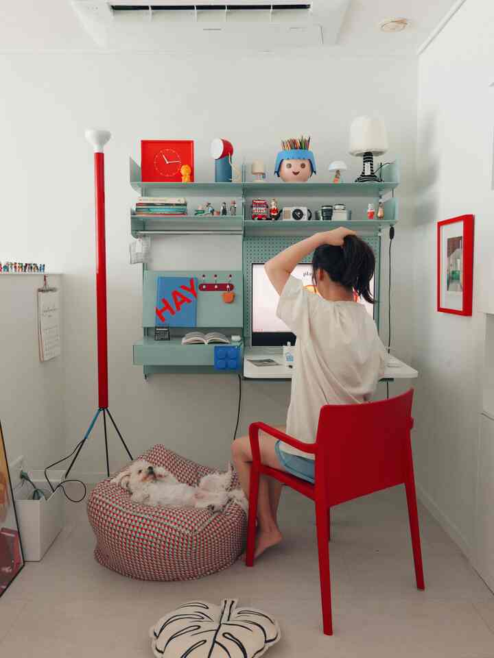 A mint and red toned study featuring a computer desk, red armchair, and a dog resting on a bean bag in a cozy home office