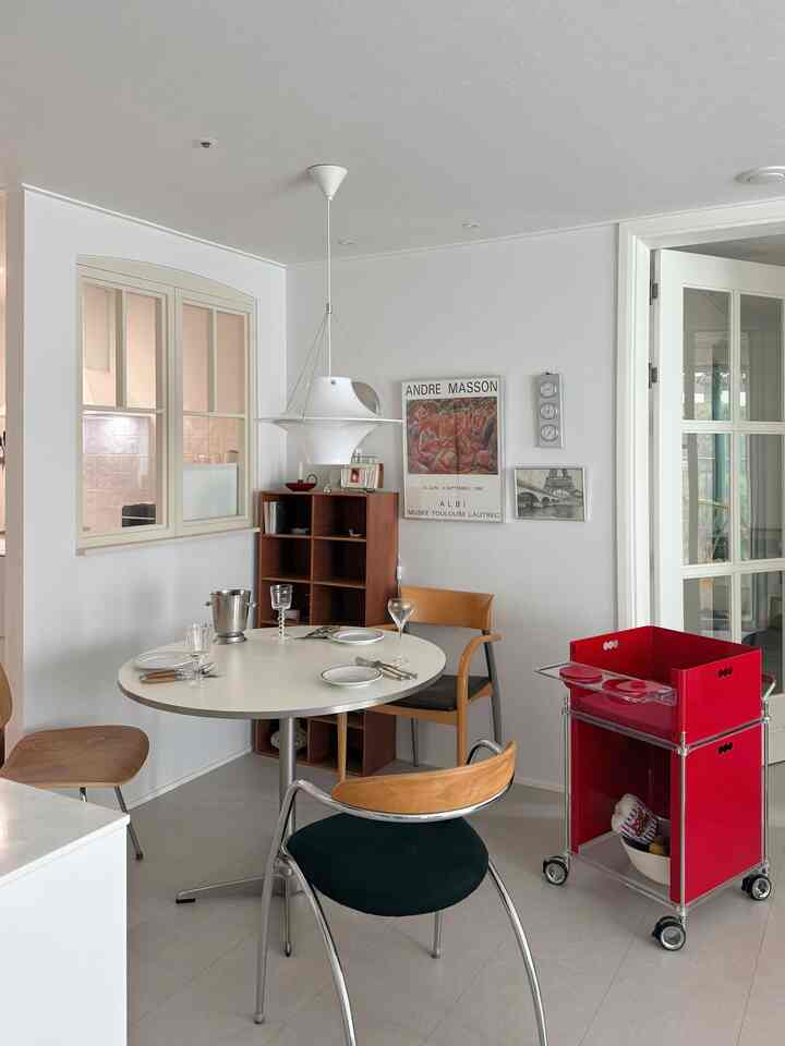 A white and wood-toned dining room featuring a round dining table and chairs, presenting a minimal and modern atmosphere