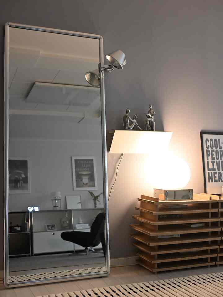 Sky blue toned living room featuring a mid-century modern full-length mirror, rug, and silver industrial decor creating a modern atmosphere