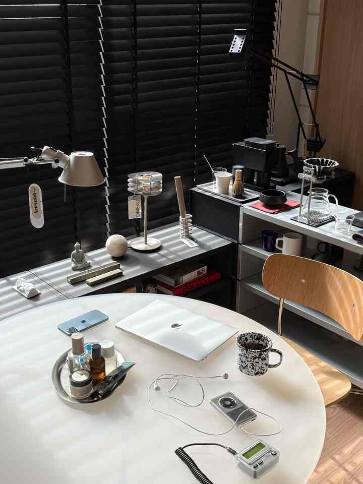 Modern, clean home office and home cafe space featuring black blinds and a white dining table