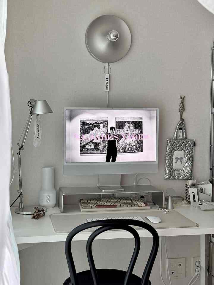 Silver and white toned home office featuring a desk, monitor, silver lamps, and a neatly organized modern workspace