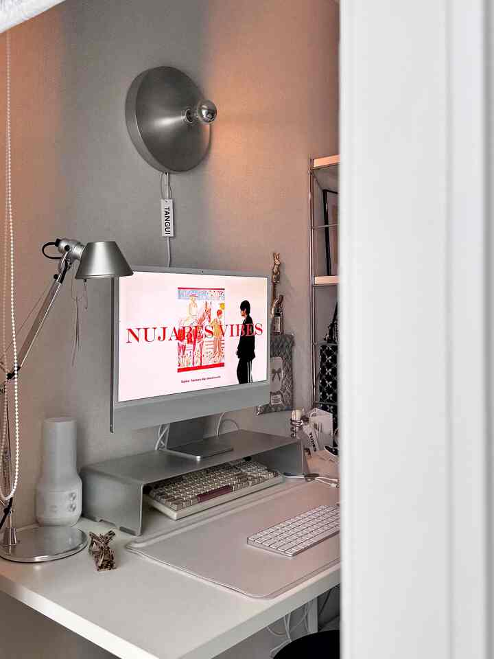 Silver and white toned small home office featuring a silver wall sconce and a modern desk creating a neat workspace