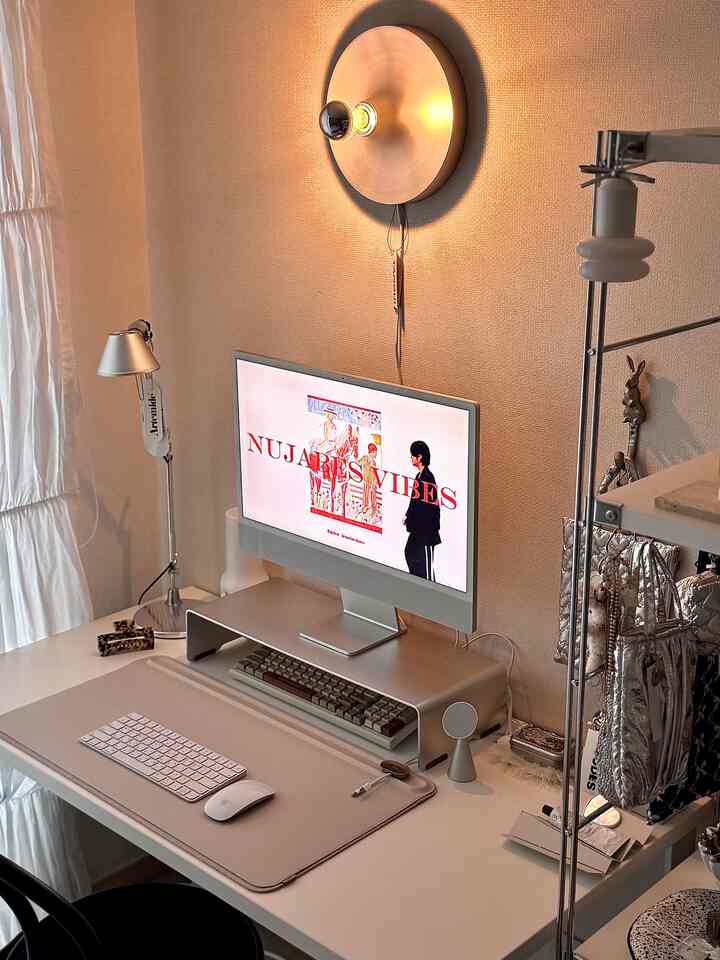 Silver and white tone home office space featuring a monitor and desk lamp with a clean, organized workspace