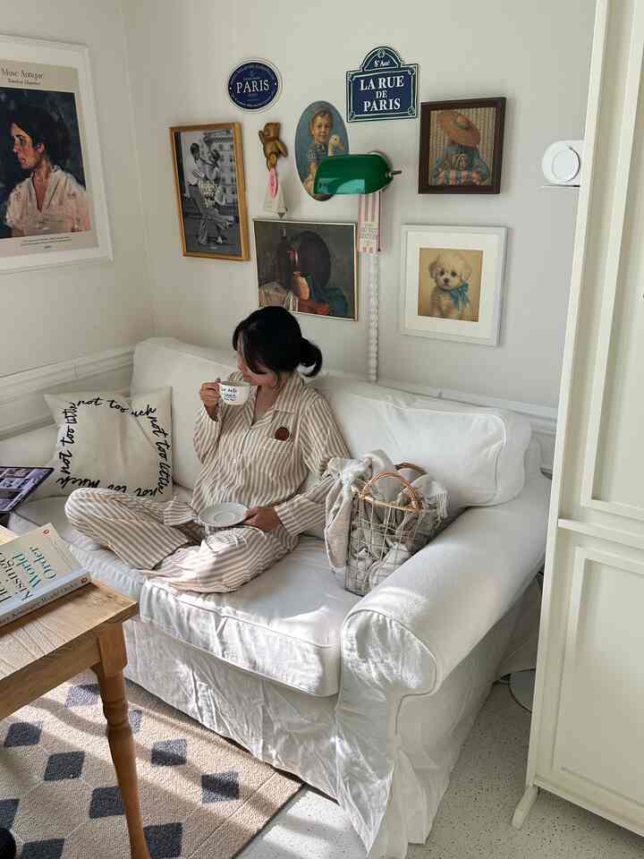 Small living room in white and beige tones featuring a white sofa and vintage posters, creating a cozy atmosphere