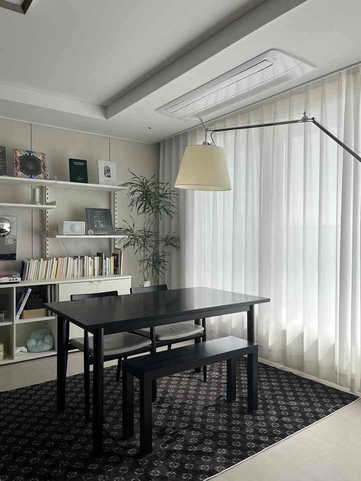ホワイトカーテンとブラックのダイニングテーブルが配置されたナチュラルモダンな雰囲気のダイニングスペース