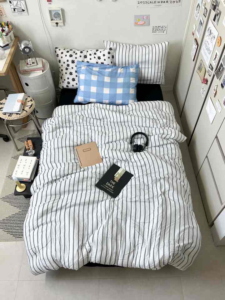 White and navy-toned single bedroom featuring a neatly made bed and a desk, creating a simple and cozy atmosphere
