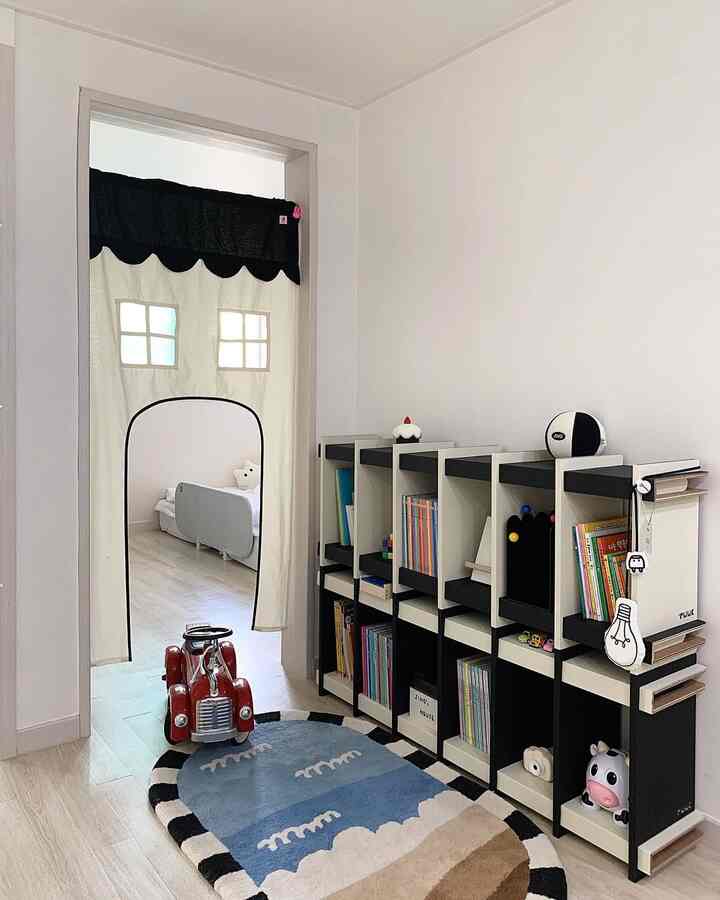白を基調とした子供部屋、ドアカーテンと本棚が配置された清潔でかわいらしい空間