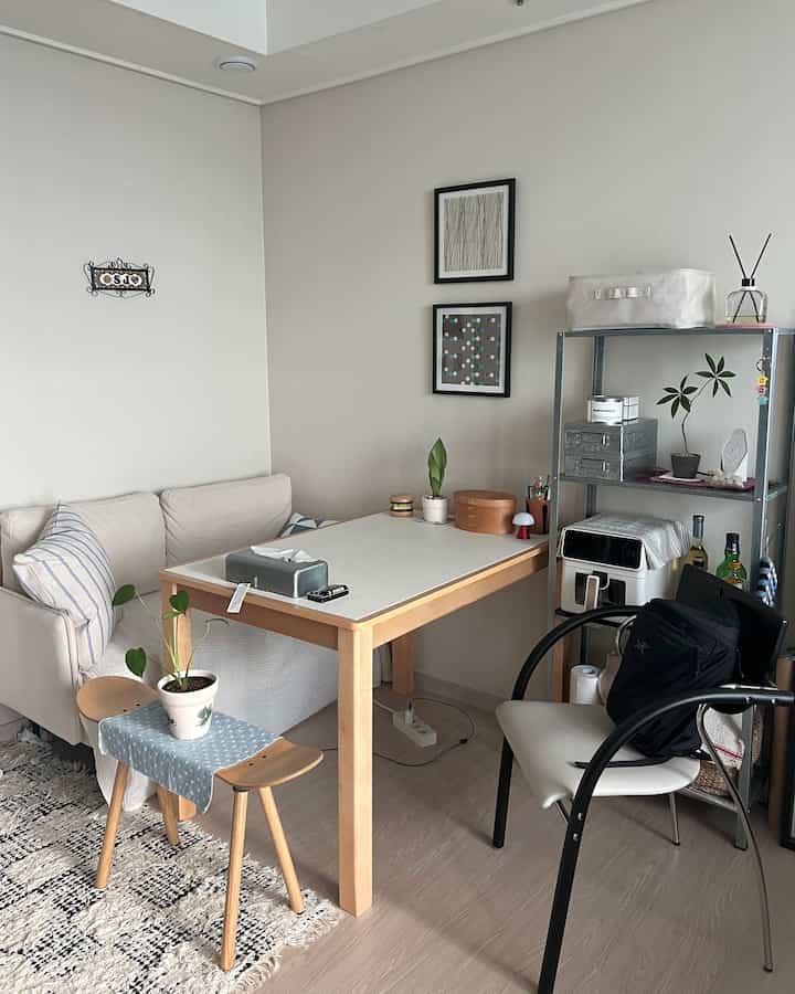 Ivory and wood-toned studio apartment featuring a desk, sofa, and shelving, creating a cozy and tidy atmosphere