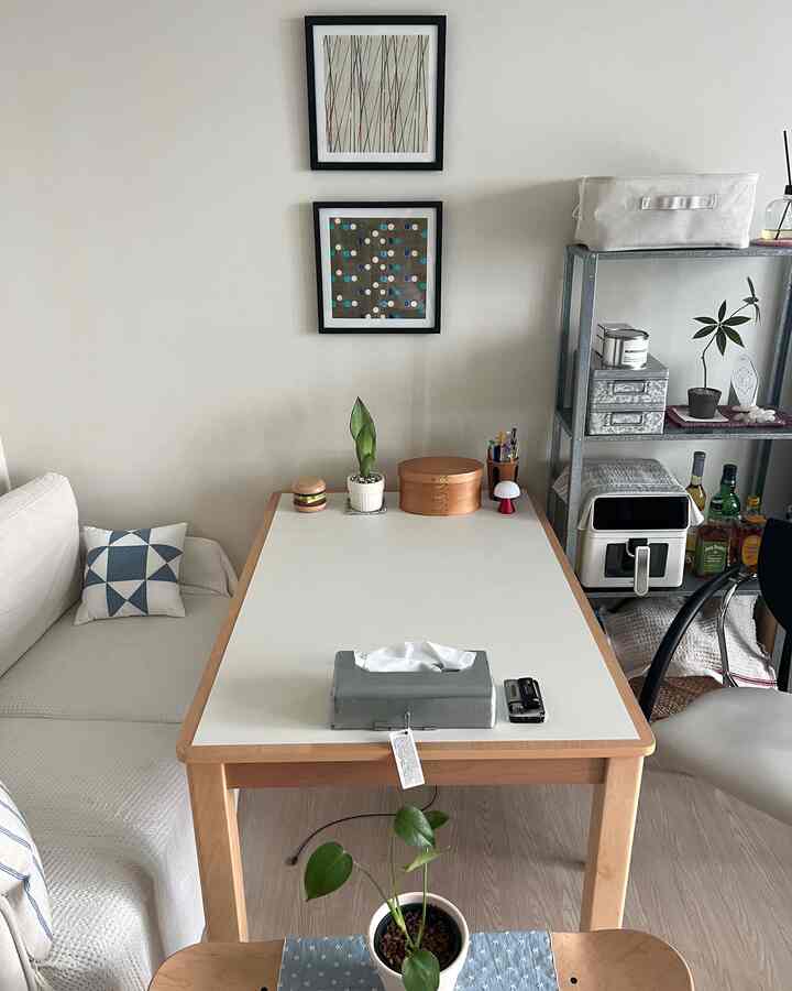 ナチュラルな木目調と白を基調としたダイニングルーム、ソファやダイニングテーブル、棚が配置された落ち着きのある空間