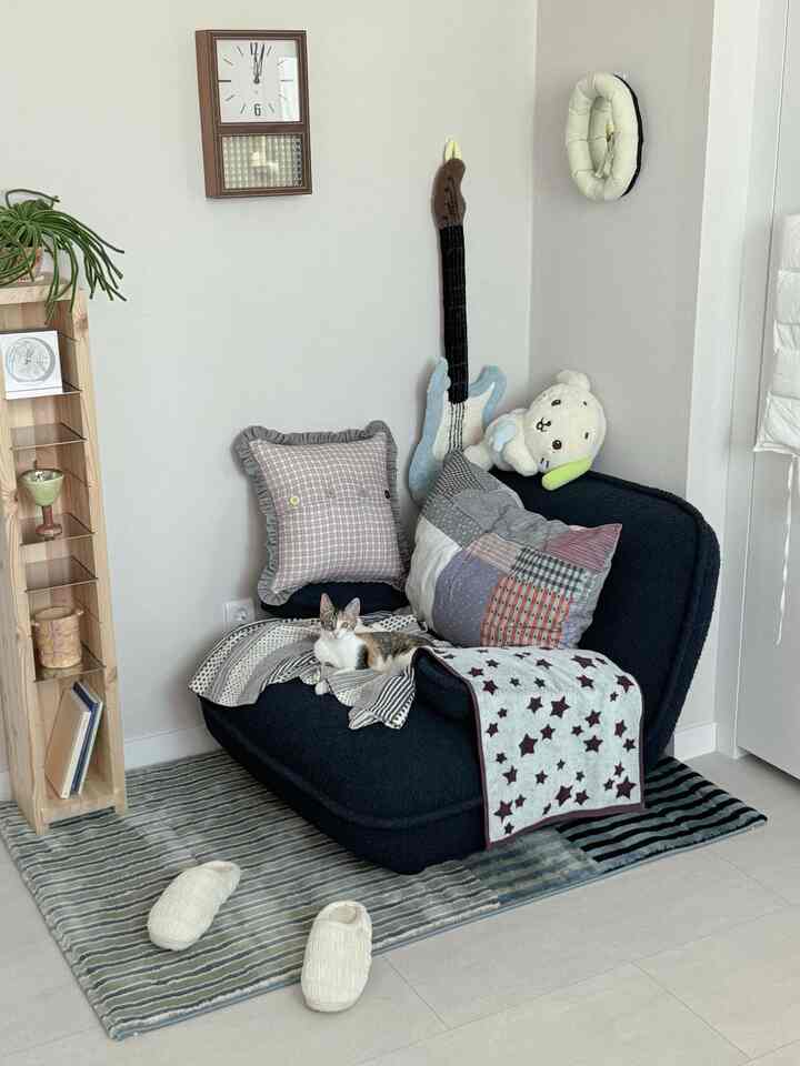 白い壁と床にネイビーのソファとラグが配置された居心地の良いリビング、ソファの上に猫がくつろいでいる