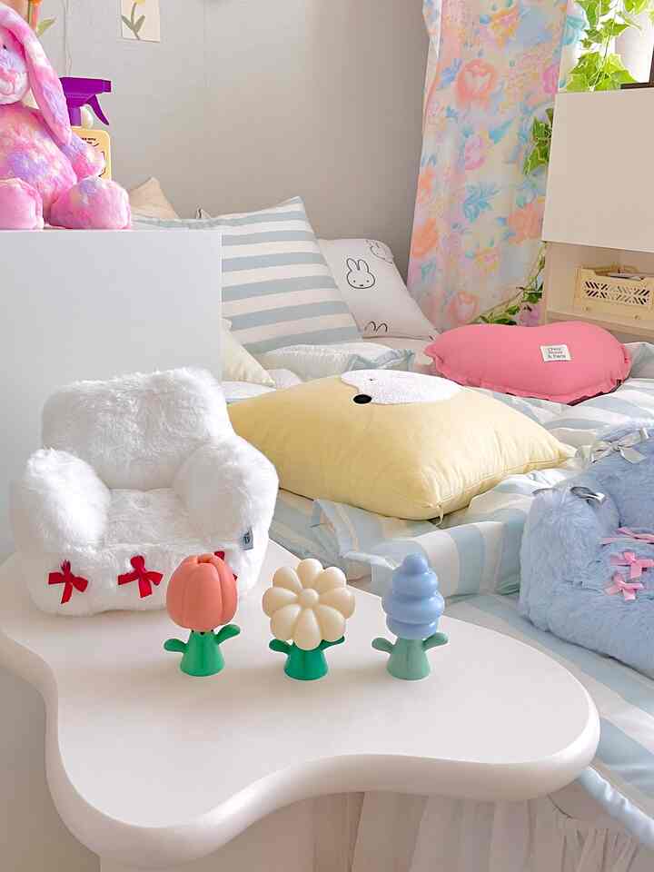 白とパステル調の寝室、かわいいクッションと子供用おもちゃが配置された雰囲気のあるインテリア
