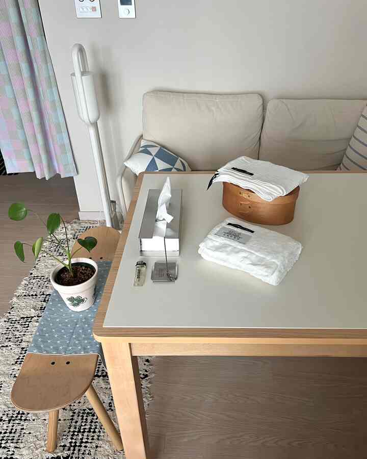 白い壁と茶色の木目調ダイニングテーブルとスツールが配置されたナチュラルモダンなリビングスペース