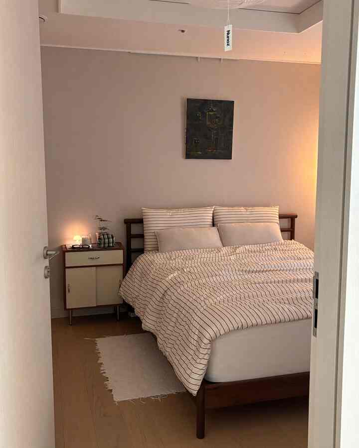 A beige-walled bedroom featuring a brown wooden bed with simple and natural ambiance