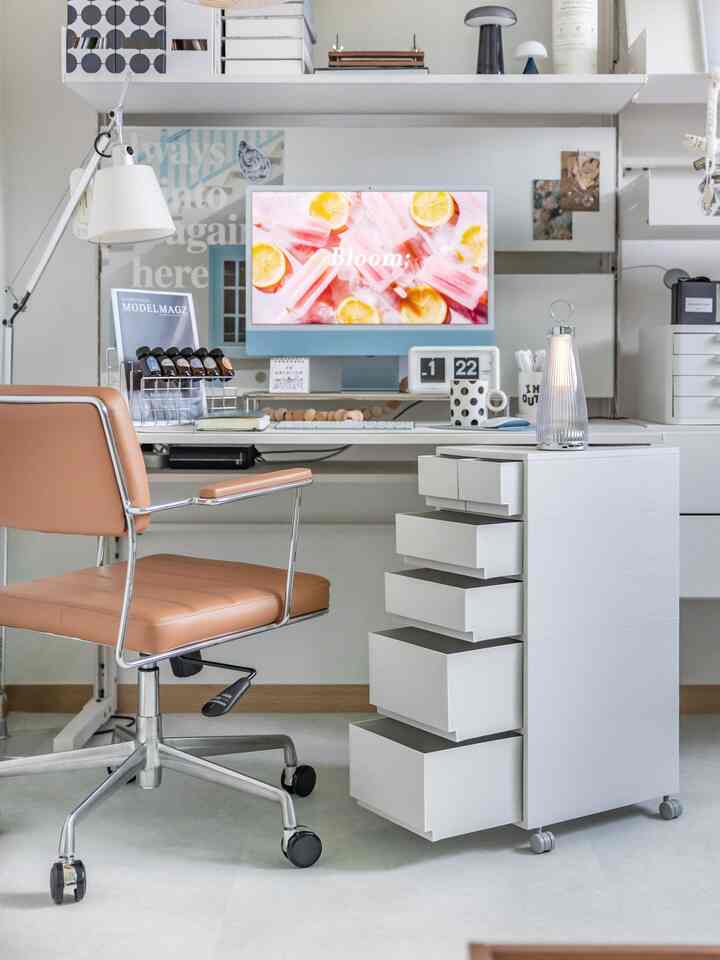 白を基調としたホームオフィス、移動式引き出しやデスク、ブラウンのオフィスチェアが配置された清潔感のある作業空間