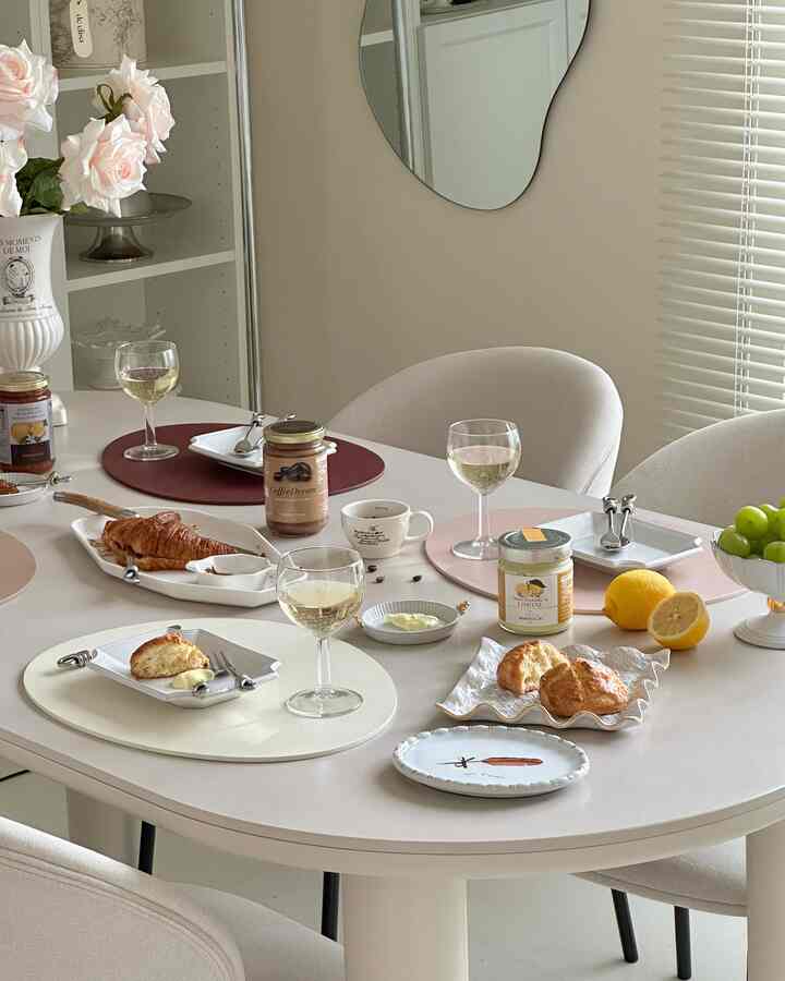 ベージュとホワイトの色調のダイニングルーム、クロワッサンとスコーンが置かれたテーブルとワイングラスが配置された雰囲気のあるおうちカフェインテリア