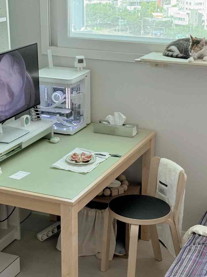 白と木目調のコンパクトなホームオフィス、窓辺のキャットタワーで猫が休んでいるモダンなインテリア