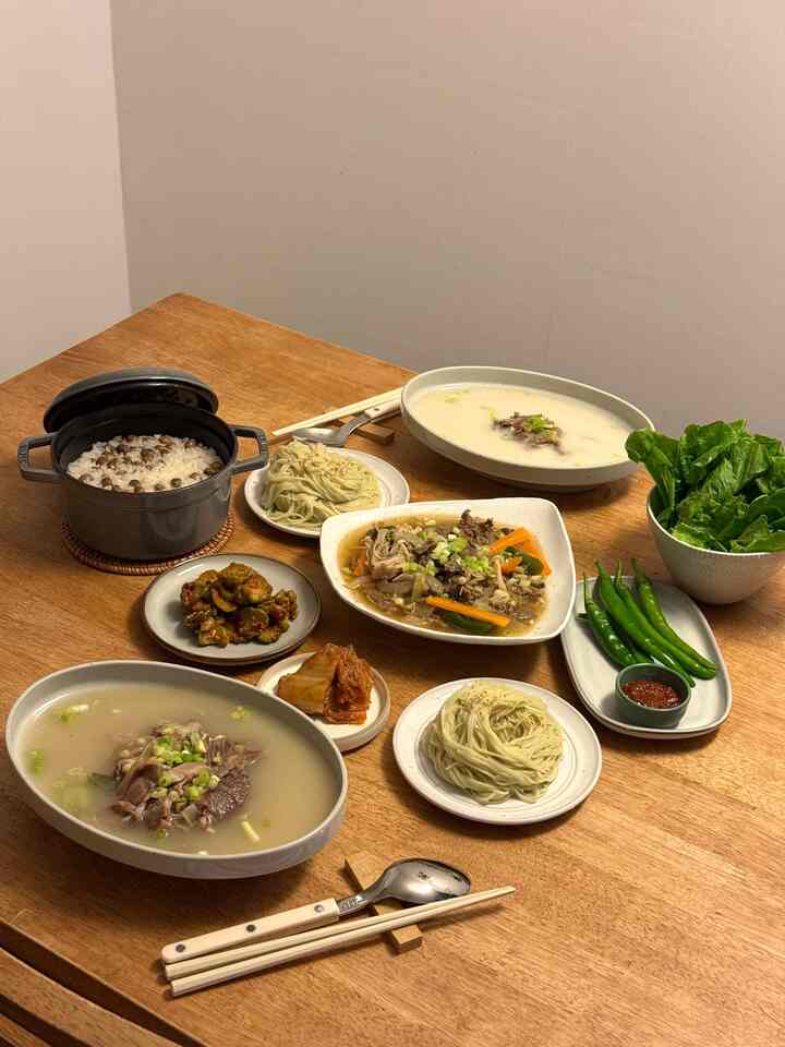 暖かみのあるブラウンの色調が特徴のキッチンのダイニングテーブルに、伝統的な韓国料理と器が配置された自然で落ち着いたインテリア