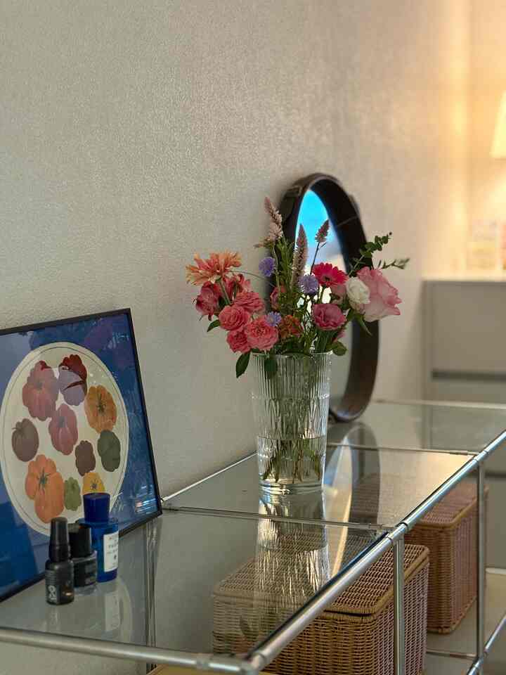 白い壁とナチュラルカラーのラタンバスケットがあるウォークインクローゼット、花瓶と照明が配置された清潔感のある空間