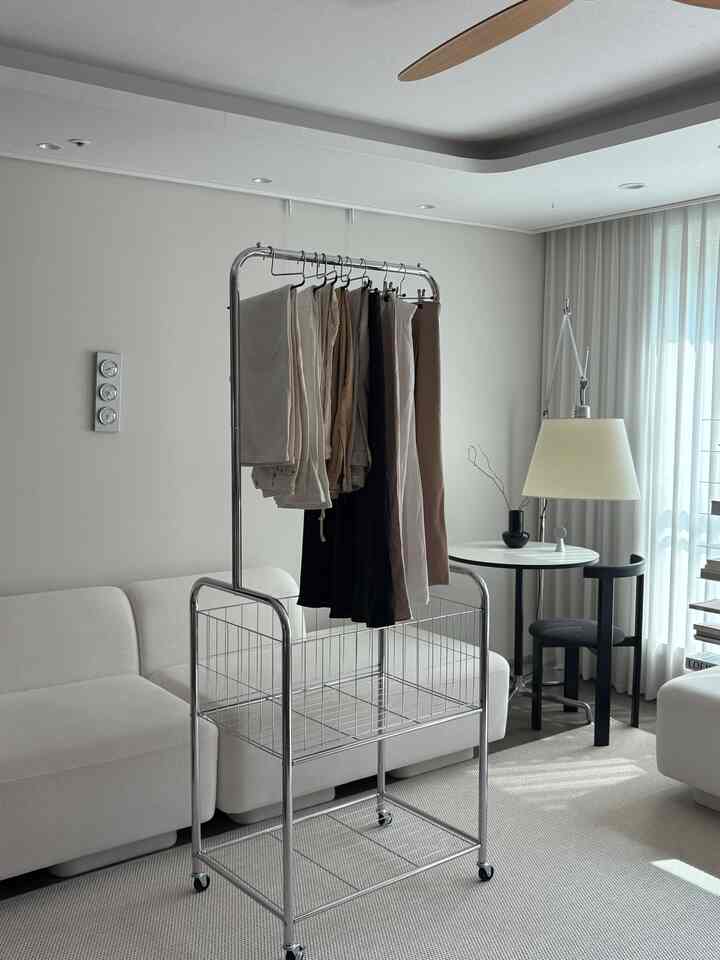 白とクロームのトーンが調和するモダンなリビング、移動式ハンガーラックとソファが配置されたすっきりとした空間