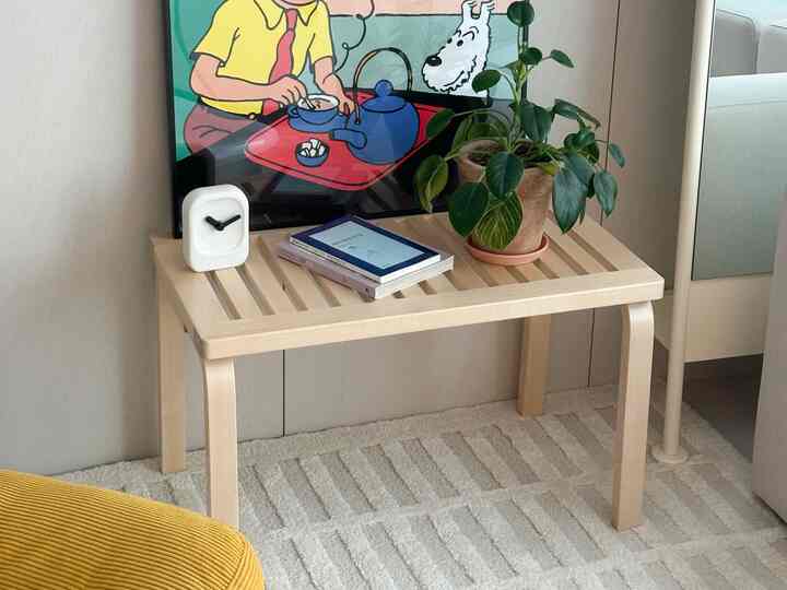 ナチュラルな木目調とホワイトのリビング、テーブルには時計と植物が置かれた雰囲気のあるインテリア