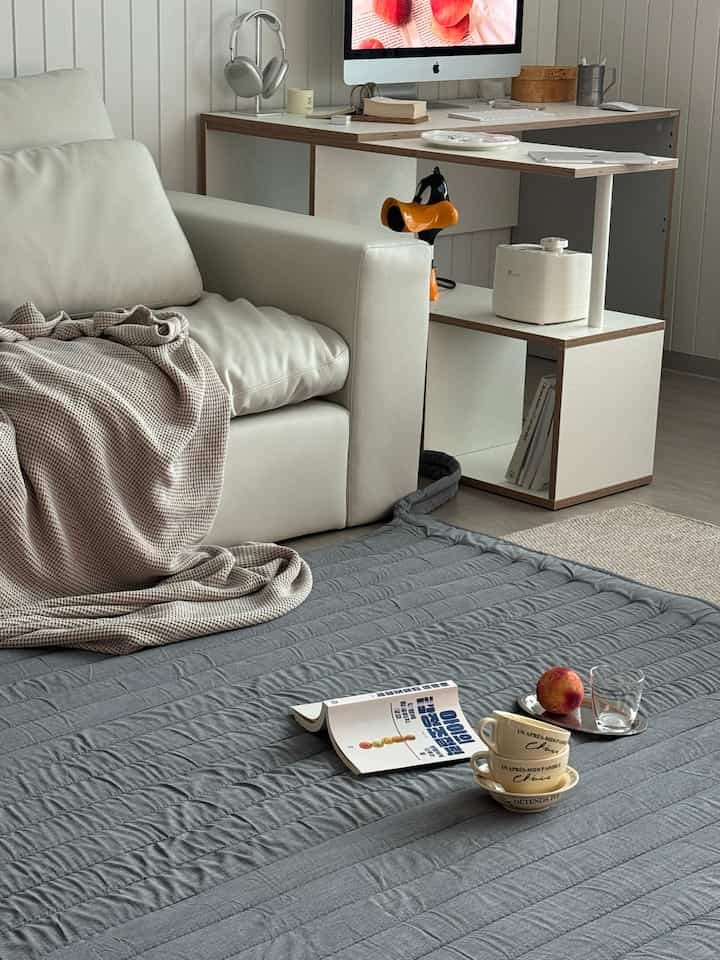 White and natural toned living room featuring a sofa and home office desk with simple modern style