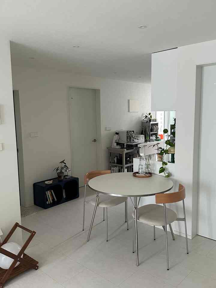 白と木目調のリビング、モダンなクロム脚の円形テーブルダイニングチェアが配置されたシンプルで清潔感のあるインテリア