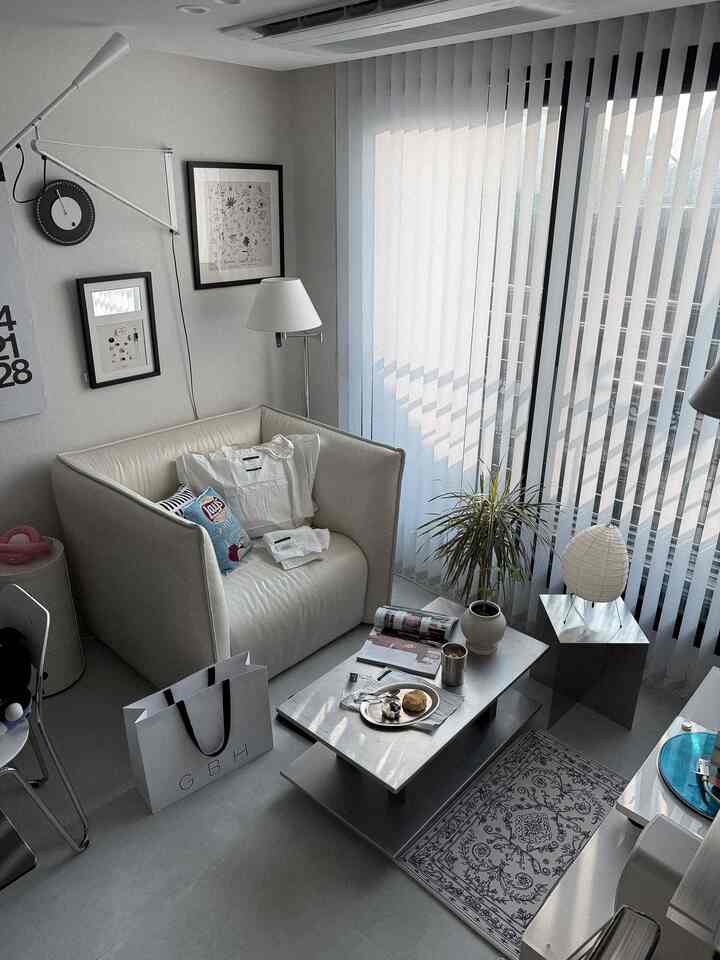 白とベージュのトーンのモダンなリビング、1人用アームチェアとコーヒーテーブル、フロアランプが配置された洗練されたインテリア