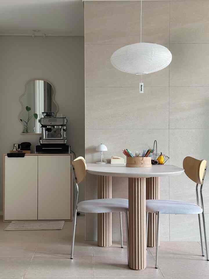 ベージュの壁と木目調インテリアが調和したダイニングルーム、セラミックのテーブルと木製チェアが配置された雰囲気のある空間