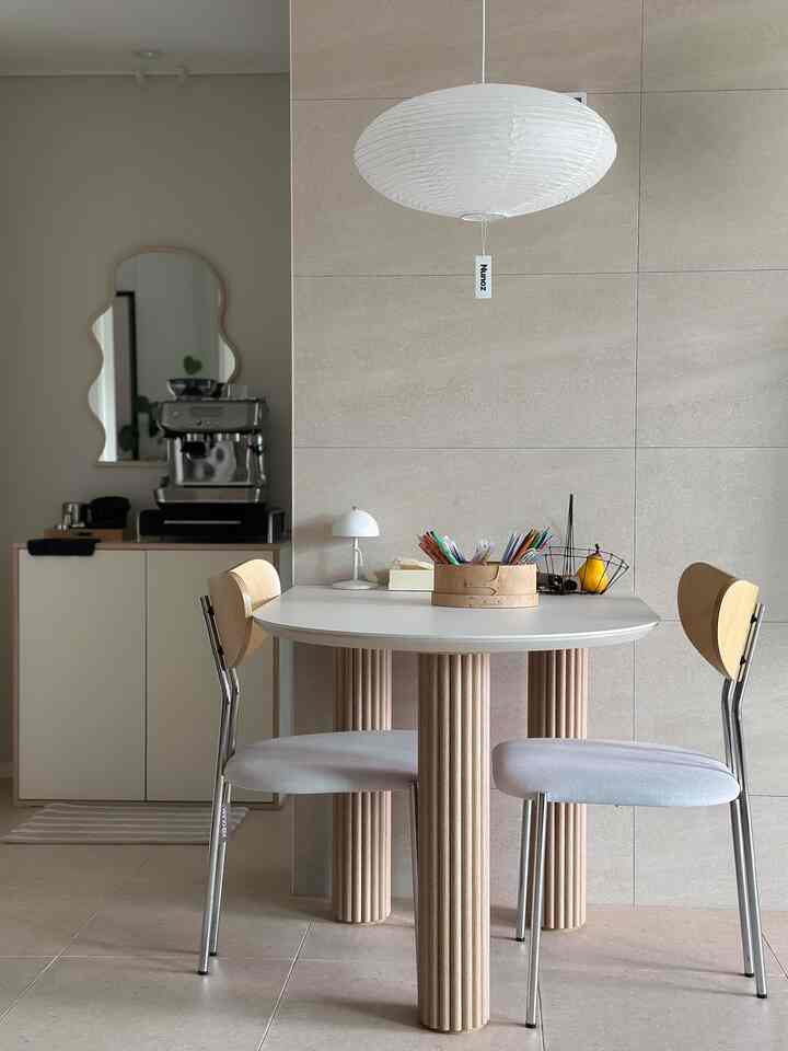 ナチュラルな色調の二人用ダイニングスペース、コーヒーマシンとミニマルなインテリアが配置されたカフェ風の雰囲気のある空間