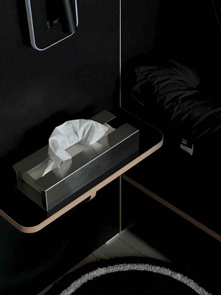 黒とシルバーのトーンのバスルーム、ステンレス製ティッシュケースと8ボール柄のラグが配置されたモダンな印象的な空間