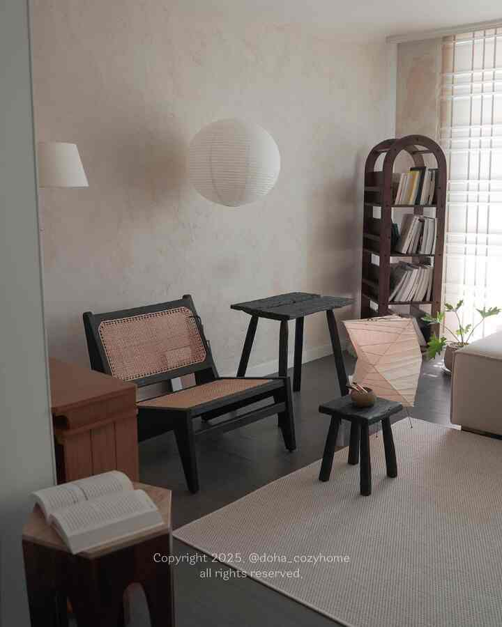 ナチュラルカラーのリビングルーム、黒い木製家具と本棚が配置された落ち着いた雰囲気のインテリア