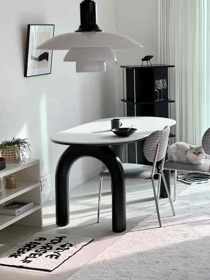 Simple modern dining room in white and black tones, featuring a pendant light and houndstooth dining chairs creating a harmonious atmosphere
