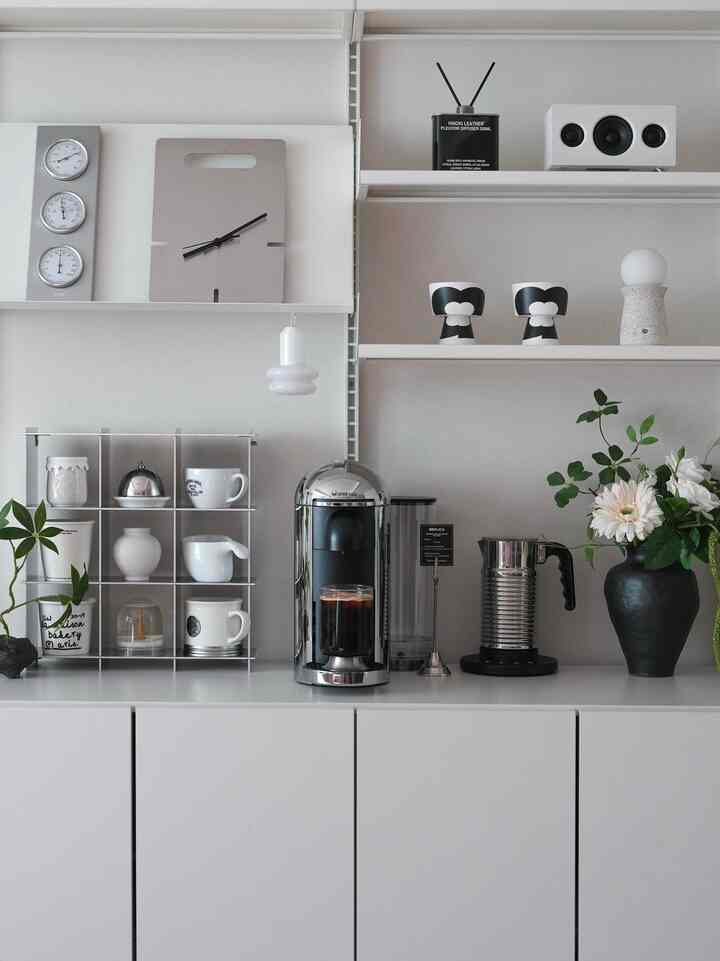 White and gray toned kitchen area featuring Nespresso machine and cups, creating a minimal home cafe atmosphere