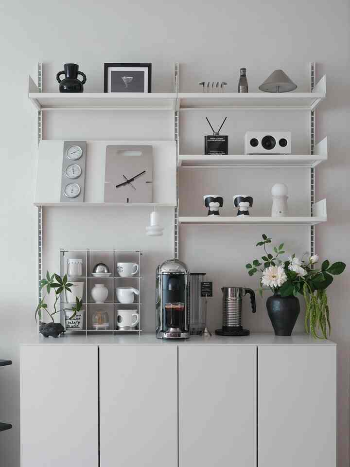 White-toned living room featuring a modern cabinet with chrome Nespresso machine and objets, creating a stylish home cafe space
