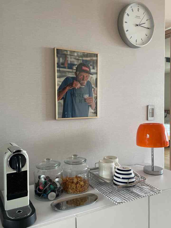 Minimal kitchen space in white and orange tones, featuring a coffee machine and neatly arranged kitchen essentials