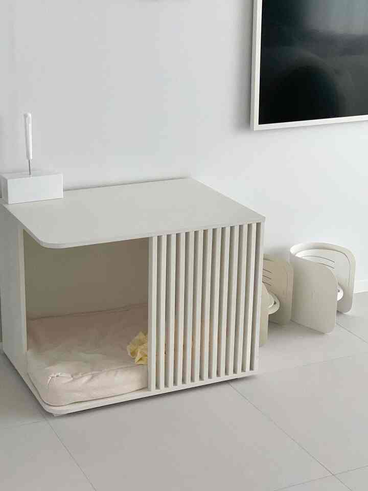 明るいホワイトとナチュラルトーンの空間にモダンなデザインの犬のウッドハウスとペット用品が配置されたミニマルなインテリア