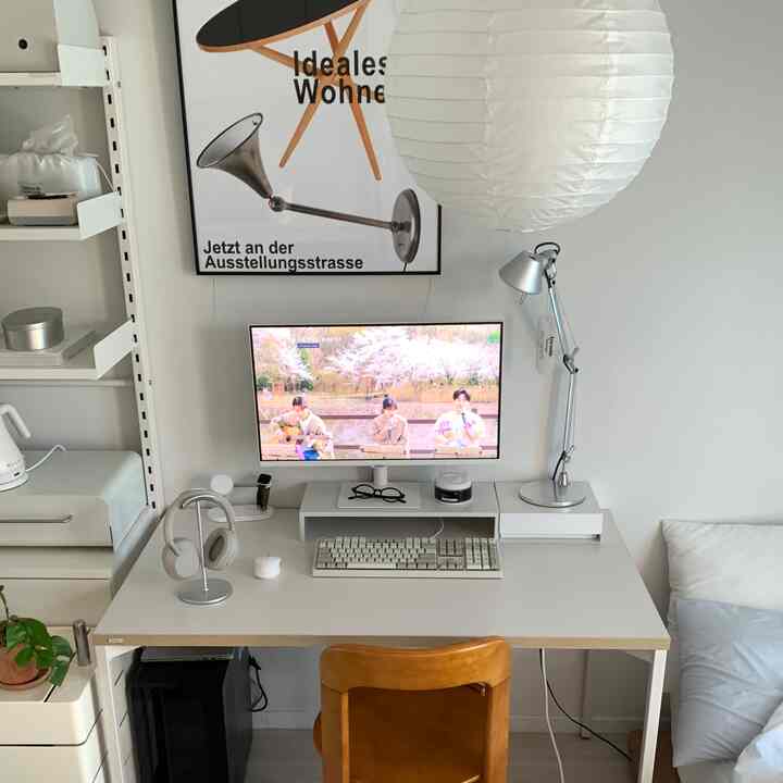 白と木目調の調和が取れたワンルームのホームオフィス、モニターと照明が配置されたすっきりしたデスク空間