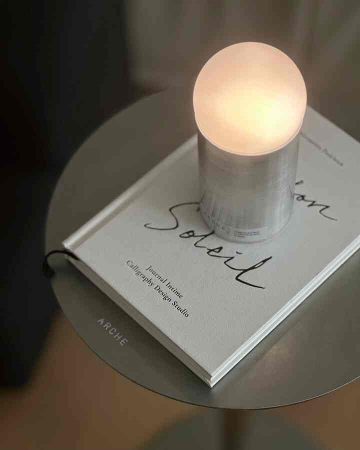 A modern, simple space featuring a charcoal-toned gap storage side table with a round table lamp on top