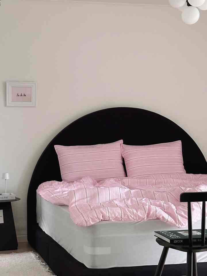 Simple modern bedroom with black semi-circular headboard and pink striped bedding