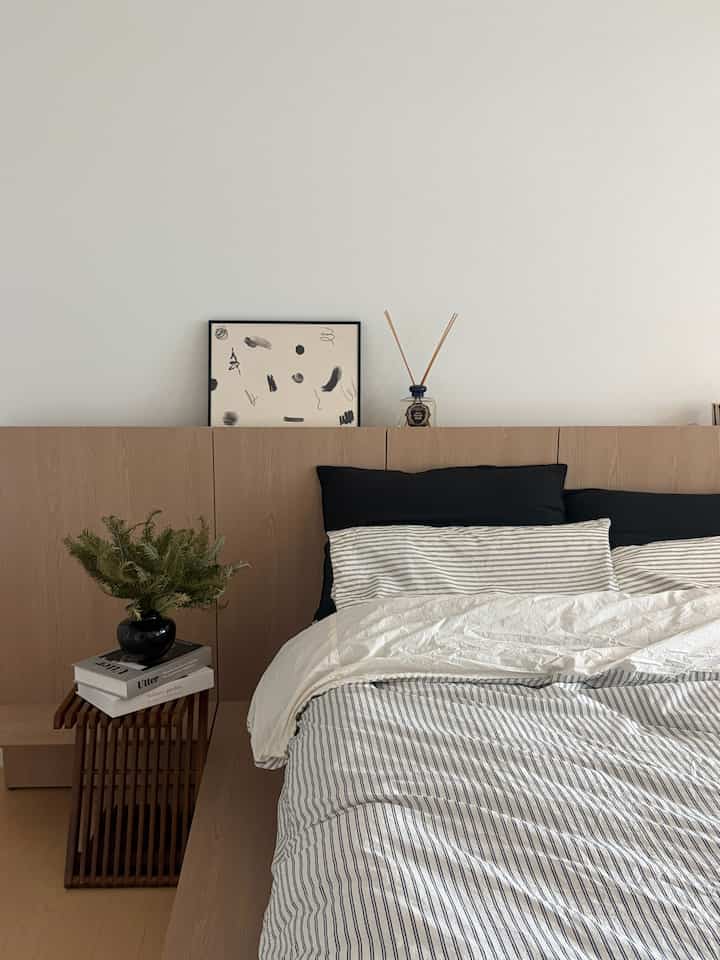 A modern bedroom in white and wood tones featuring striped duvet and simple furniture for a clean look