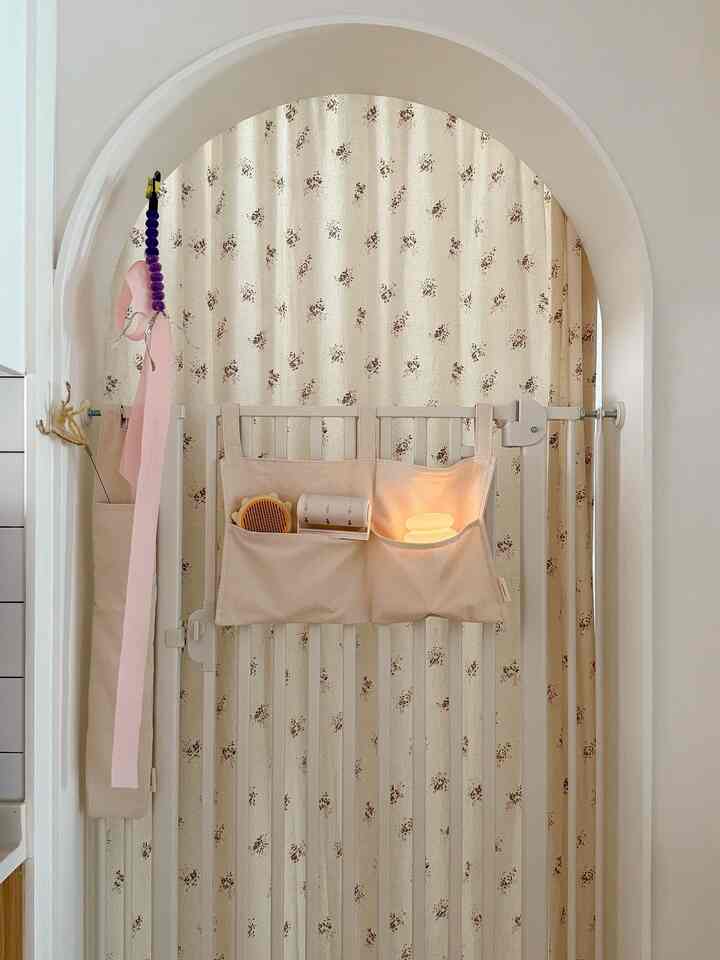 A narrow space with beige tones featuring a Safepet dog gate installed in an arched doorway with a pocket organizer, creating a neat interior