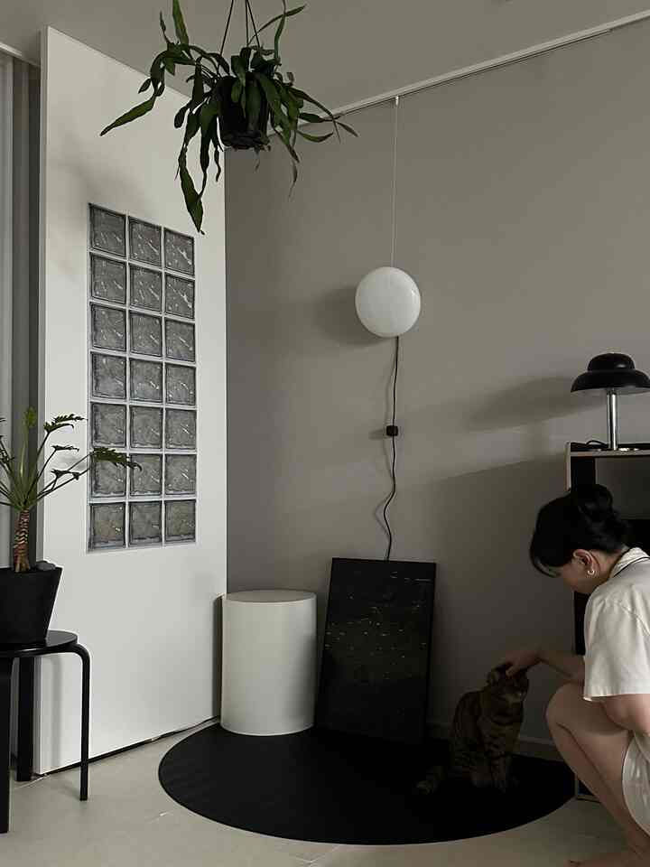 A modern and minimal living room in white and gray tones, featuring a glass block wall and wall sconce lighting