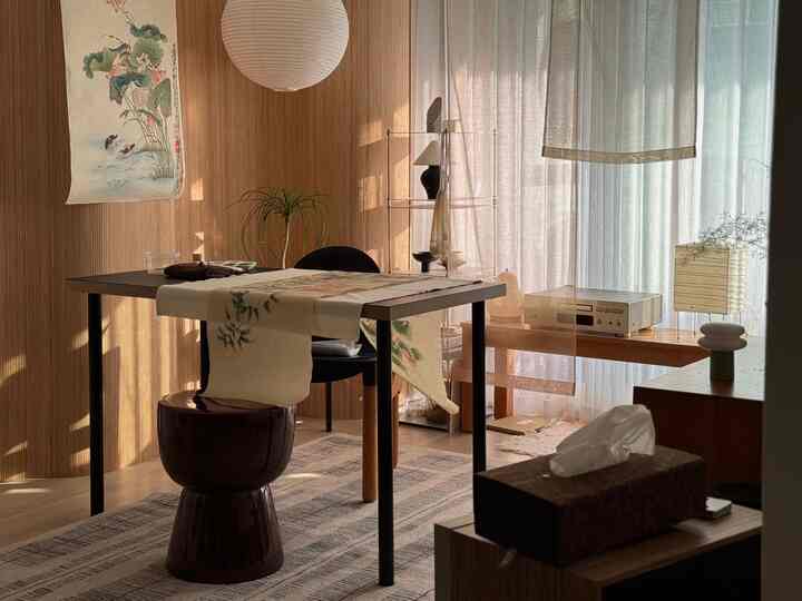 Warm beige and wood tone dining room featuring simple natural table and chairs with sheer curtains creating a cozy atmosphere