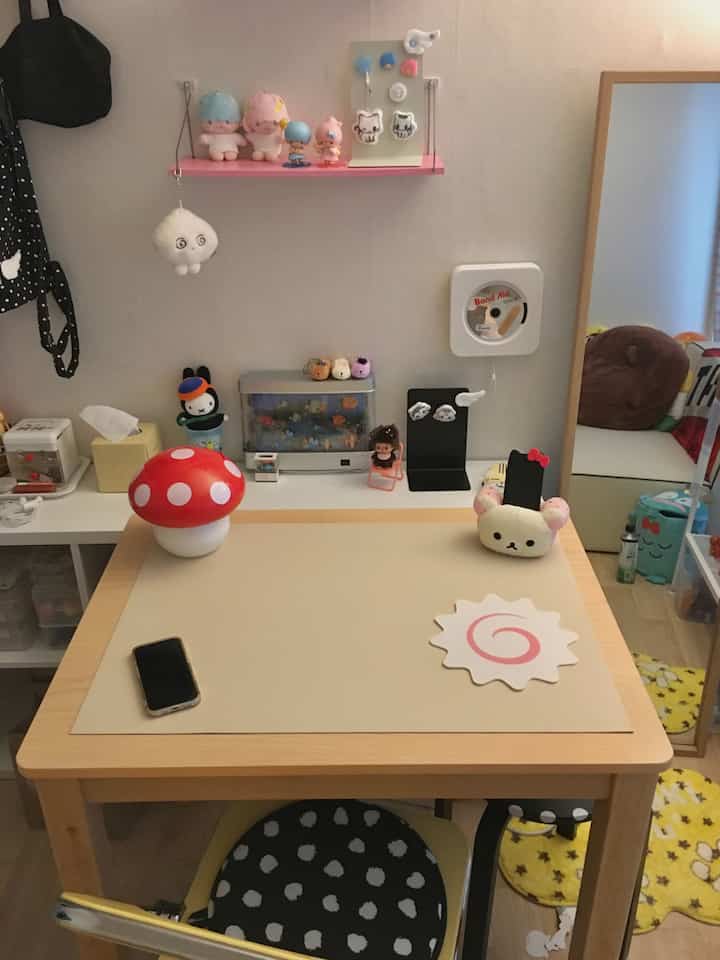 白とナチュラルカラーの子供部屋、机とピンクの棚にかわいいキャラクターが配置された雰囲気のあるインテリア