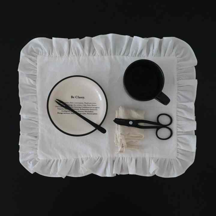 白いフリルのテーブルランナーが黒いダイニングテーブルに置かれ、クラシックな雰囲気のあるキッチンのインテリア