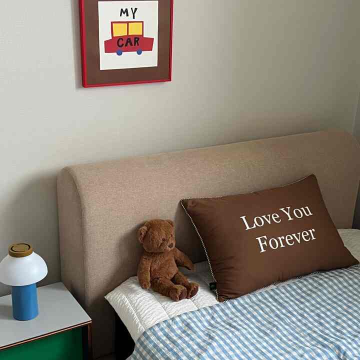 ブラウン色調の子供部屋、ぬいぐるみのクマと「Love You Forever」クッションが置かれた印象的な寝室