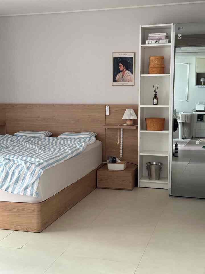 Natural wood tones and white blend in a bedroom featuring a tidy bed, nightstand, and portrait wall decor creating a cozy atmosphere